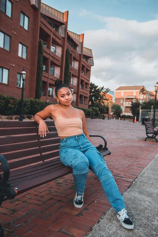 a woman sitting on top of a wooden bench, by Robbie Trevino, wearing crop top, at college, audrey plaza, basia tran