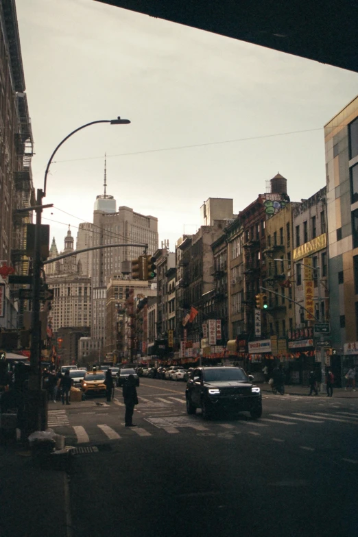 a city street filled with lots of traffic and tall buildings, a photo, trending on unsplash, harlem renaissance, 2000s photo, chinatown, ignant, gothic city streets behind her