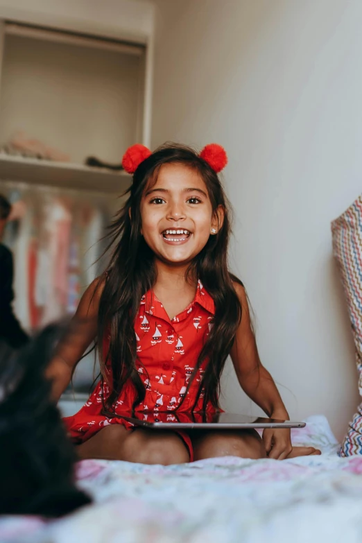 a little girl sitting on top of a bed next to a black cat, pexels contest winner, toyism, wearing a red outfit, earing a shirt laughing, indian girl with brown skin, black haired girl wearing hoodie