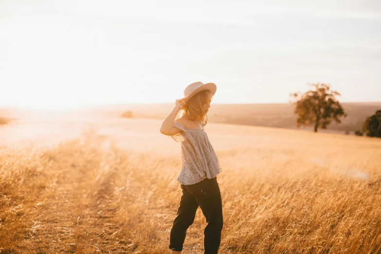 a woman standing in a field at sunset, by Maggie Hamilton, unsplash contest winner, an australian summer landscape, denim, light stubble, transparent background