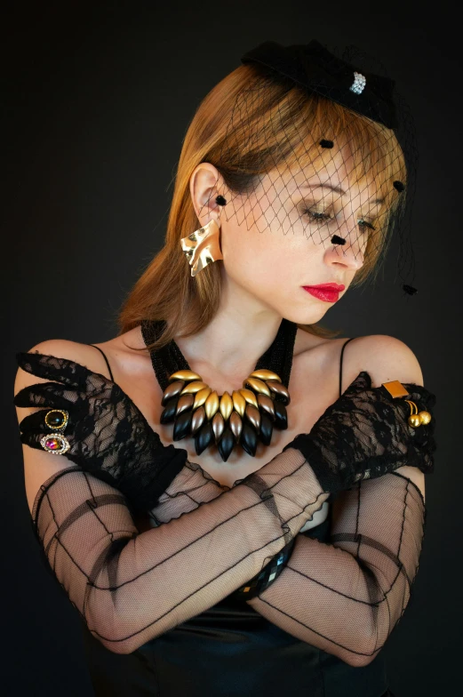 a woman in a black dress posing for a picture, inspired by Hedi Xandt, gloves and jewelry. motion, intricate gold jewlery, with shoulder pads, zoe kazan