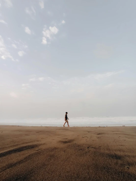 a person on a beach flying a kite, pexels contest winner, minimalism, walking to the right, black sand, looking sad, low quality footage