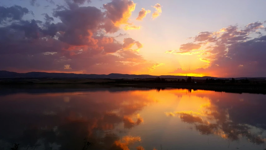 a large body of water with a sunset in the background, pexels contest winner, wyoming, dynamic reflections, instagram post, summer setting