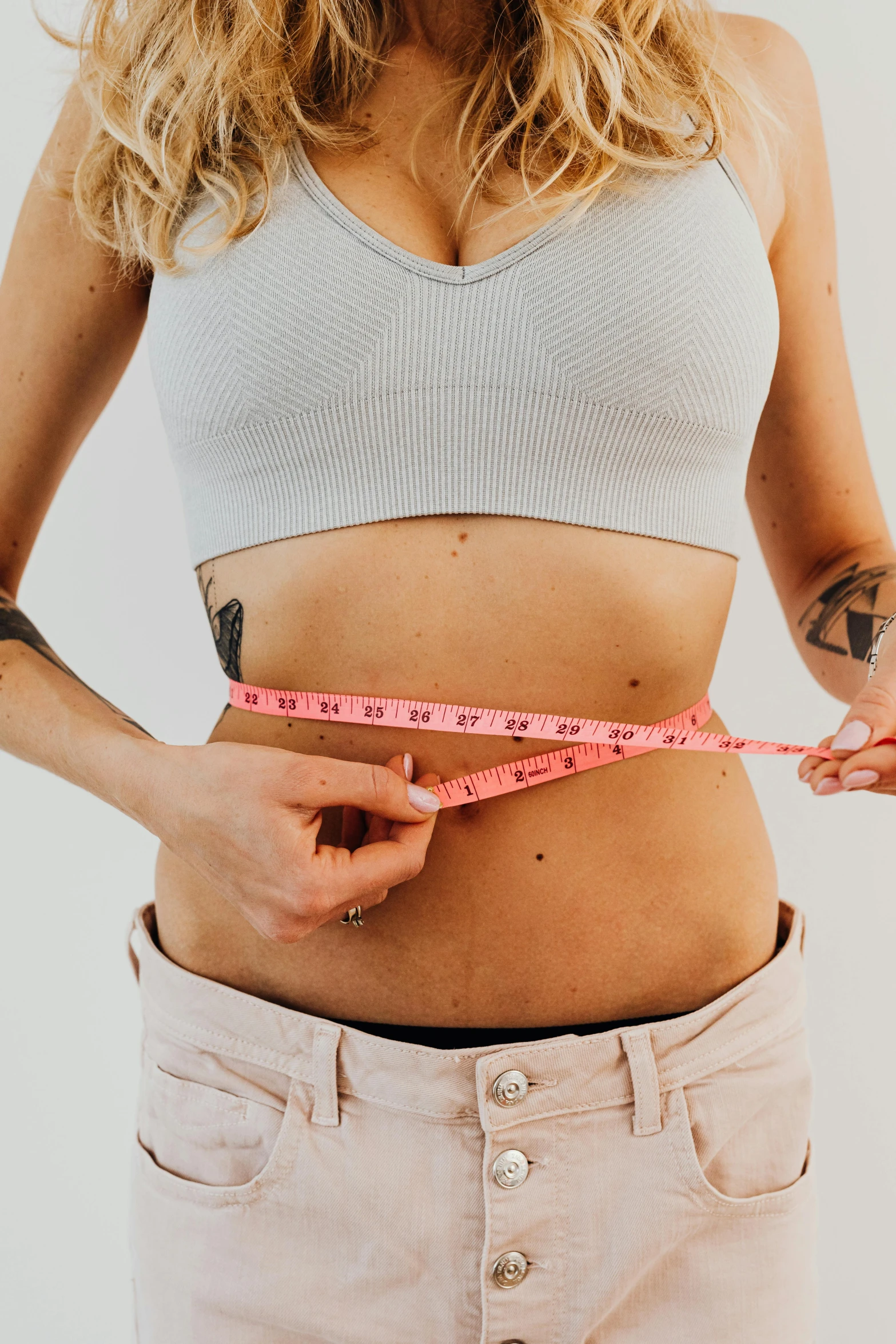 a woman measuring her waist with a tape, a colorized photo, by Nicolette Macnamara, trending on pexels, diecut, stomach skin, emily rajtkowski, half figure front