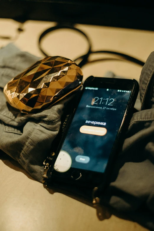 a cell phone sitting on top of a table next to a pair of jeans, by Adam Marczyński, happening, gold shirt, jewelry, organized, wearing adventuring gear