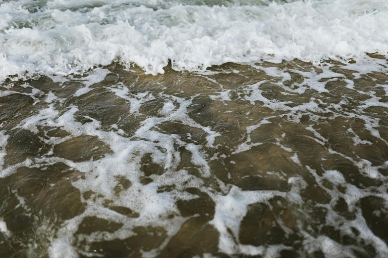 a man riding a wave on top of a surfboard, unsplash, renaissance, beach sand background, puddles of water on the ground, flowing forms, middle close up