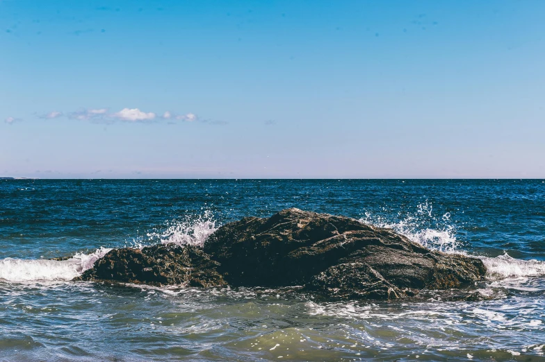 a large rock in the middle of a body of water, unsplash, blue crashing waves, sunny day at beach, profile image, landscape photo