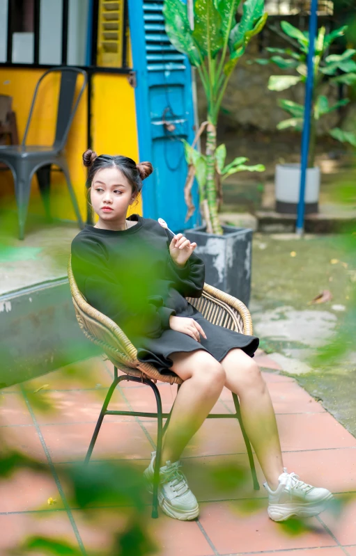 a woman sitting on a chair next to a surfboard, a portrait, inspired by Ruth Jên, pexels contest winner, chilling on a leaf, south east asian with round face, teenage girl, eating outside