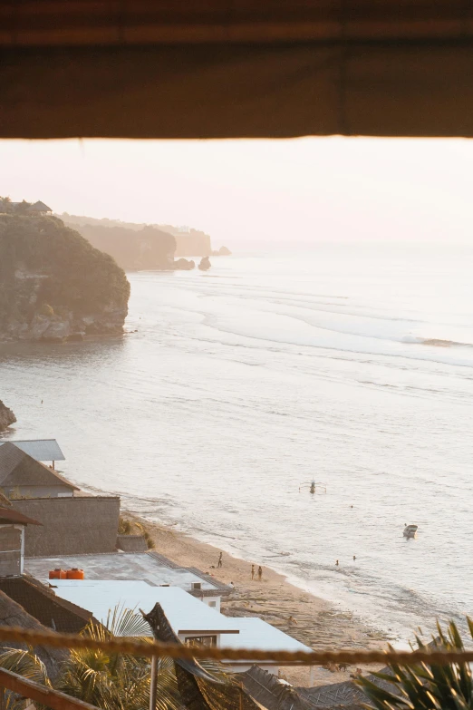 a view of a beach through a window, inspired by Andreas Gursky, pexels contest winner, bali, cliff side at dusk, surfing, low quality photo