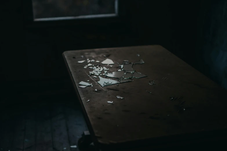 a table with broken glass on it in a dark room, by Elsa Bleda, pexels contest winner, harsh sunlight, torn paper edges, background image, in a desolate