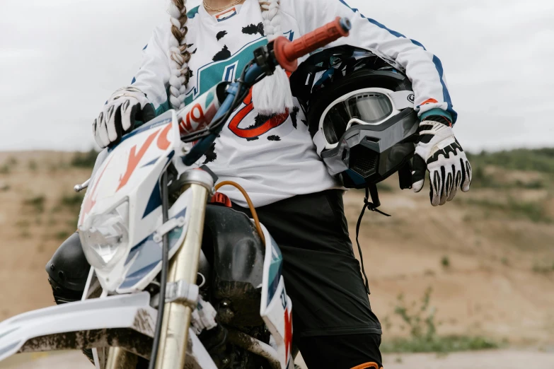 a woman riding on the back of a dirt bike, unsplash, figuration libre, white and teal garment, avatar image, close-up photo, holding helmet