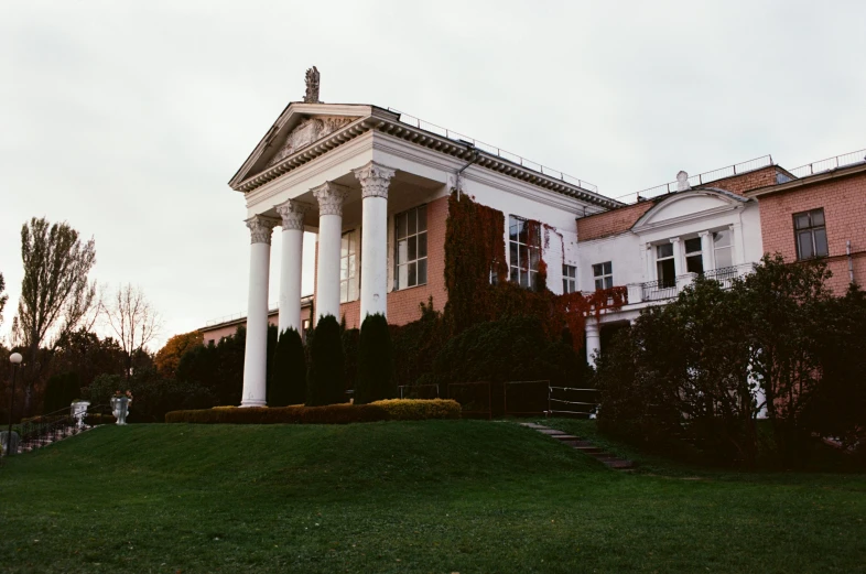 a large white building sitting on top of a lush green field, by Emma Andijewska, unsplash, neoclassicism, during autumn, vaporwave mansion, pillars, 000 — википедия