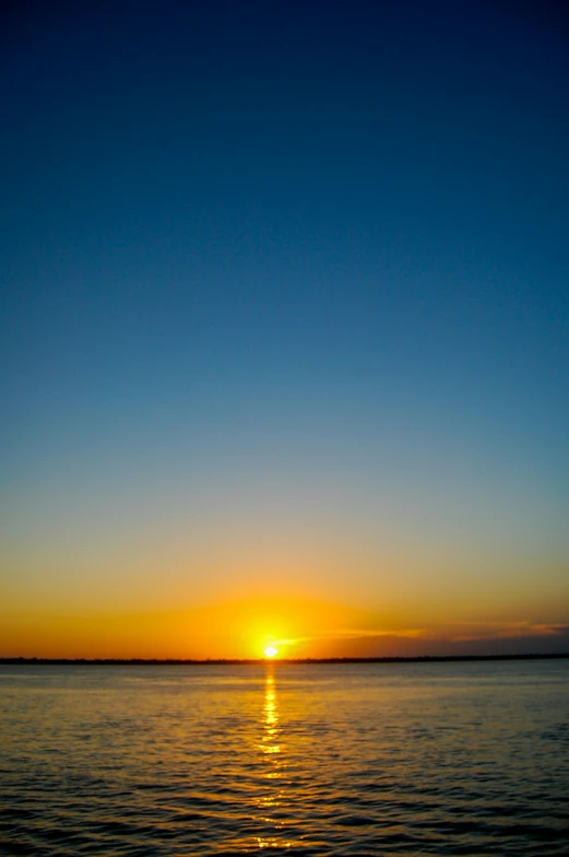 the sun is setting over a body of water, post-processed, blue - yellow sky, 8 k -