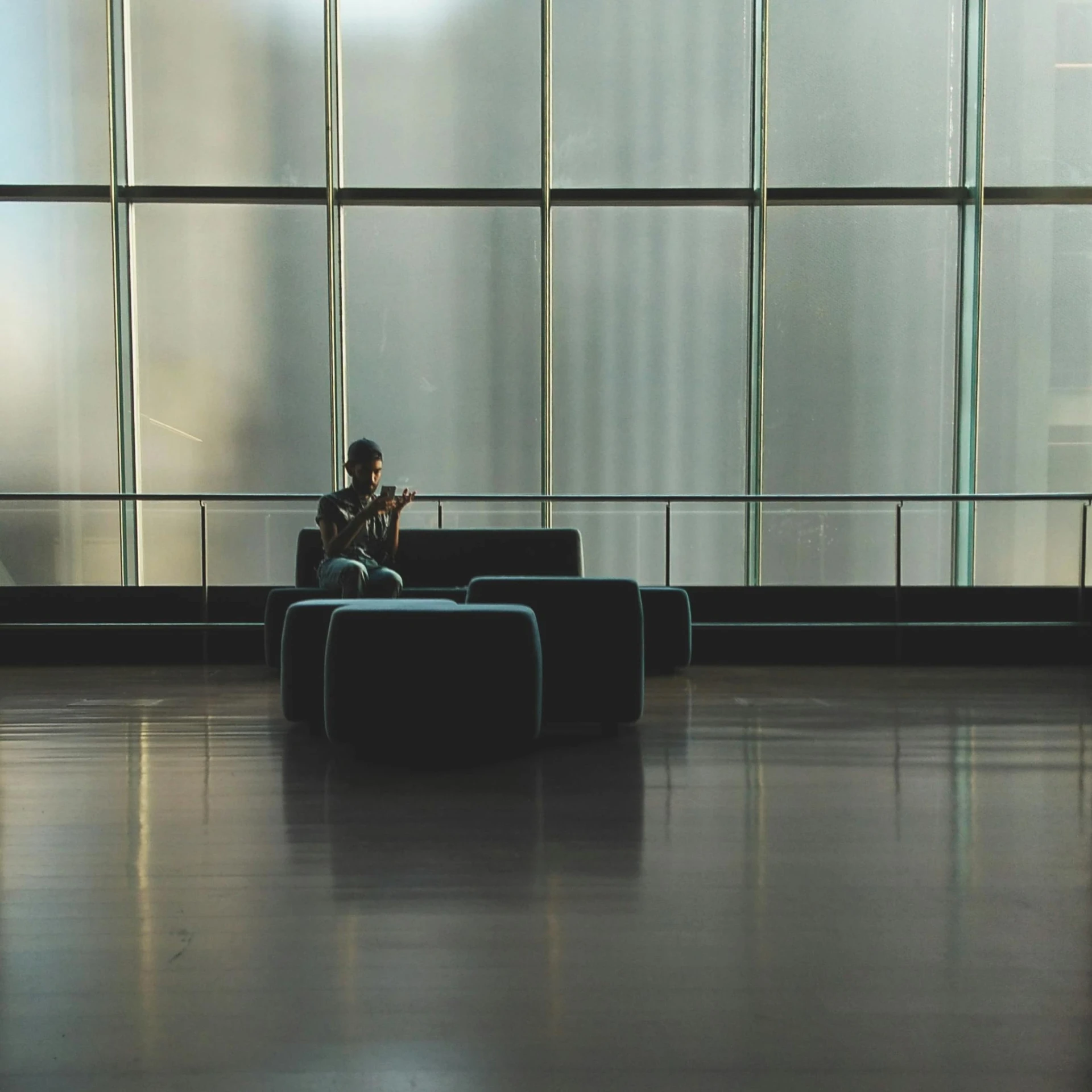 a person sitting on a couch in front of a large window, pexels contest winner, modernism, black. airports, conversation pit, phone photo, set inside of the bank