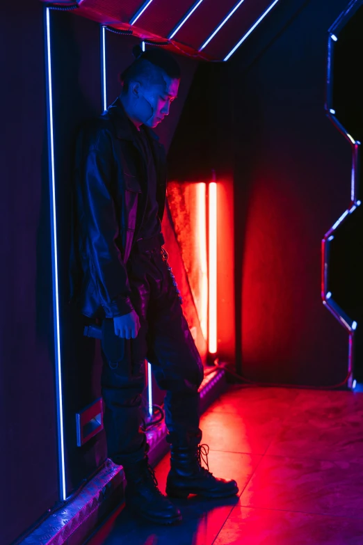 a man standing in a room with neon lights, cyberpunk art, inspired by Elsa Bleda, unsplash, leather clothing and boots, red and blue black light, fashion studio lighting, yung lean