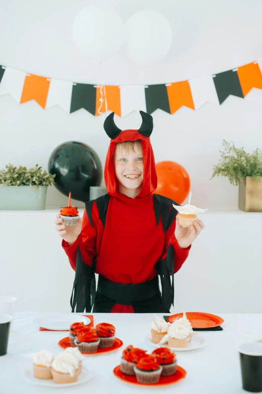 a woman in a devil costume sitting at a table with cupcakes, pexels, red haired teen boy, high resolution product photo, small, small horns