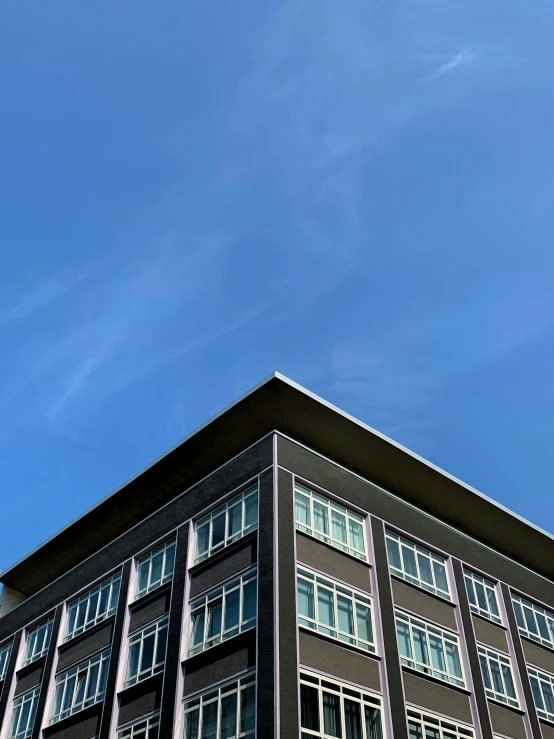 a tall building with lots of windows under a blue sky, an album cover, unsplash, background image, college, pearly sky, square