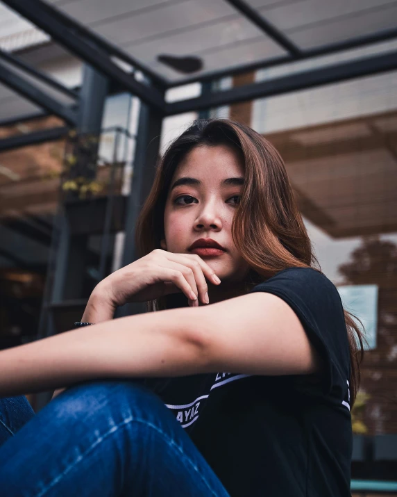 a woman sitting on the ground in front of a building, inspired by Ruth Jên, trending on unsplash, young cute wan asian face, lgbtq, standing in a restaurant, wearing a t-shirt