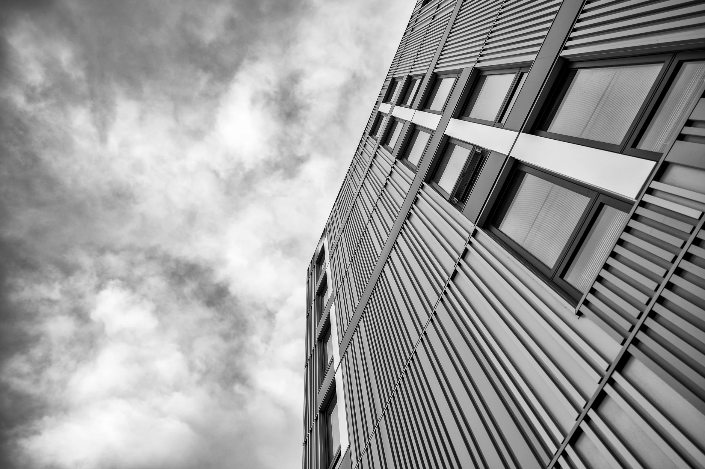 a black and white photo of a tall building, by Matthias Weischer, unsplash, square lines, metal panels, dramatic sky, low dutch angle