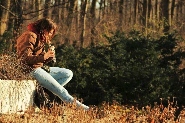 a woman sitting on a wall looking at her cell phone, pexels, romanticism, young girl playing flute, in the wood, sitting in a field of cannabis, profile image