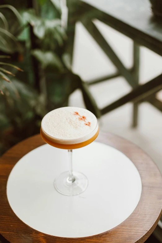 a cocktail sitting on top of a wooden table, by Nicolette Macnamara, white and orange, on a marble pedestal, colombian, multiple stories