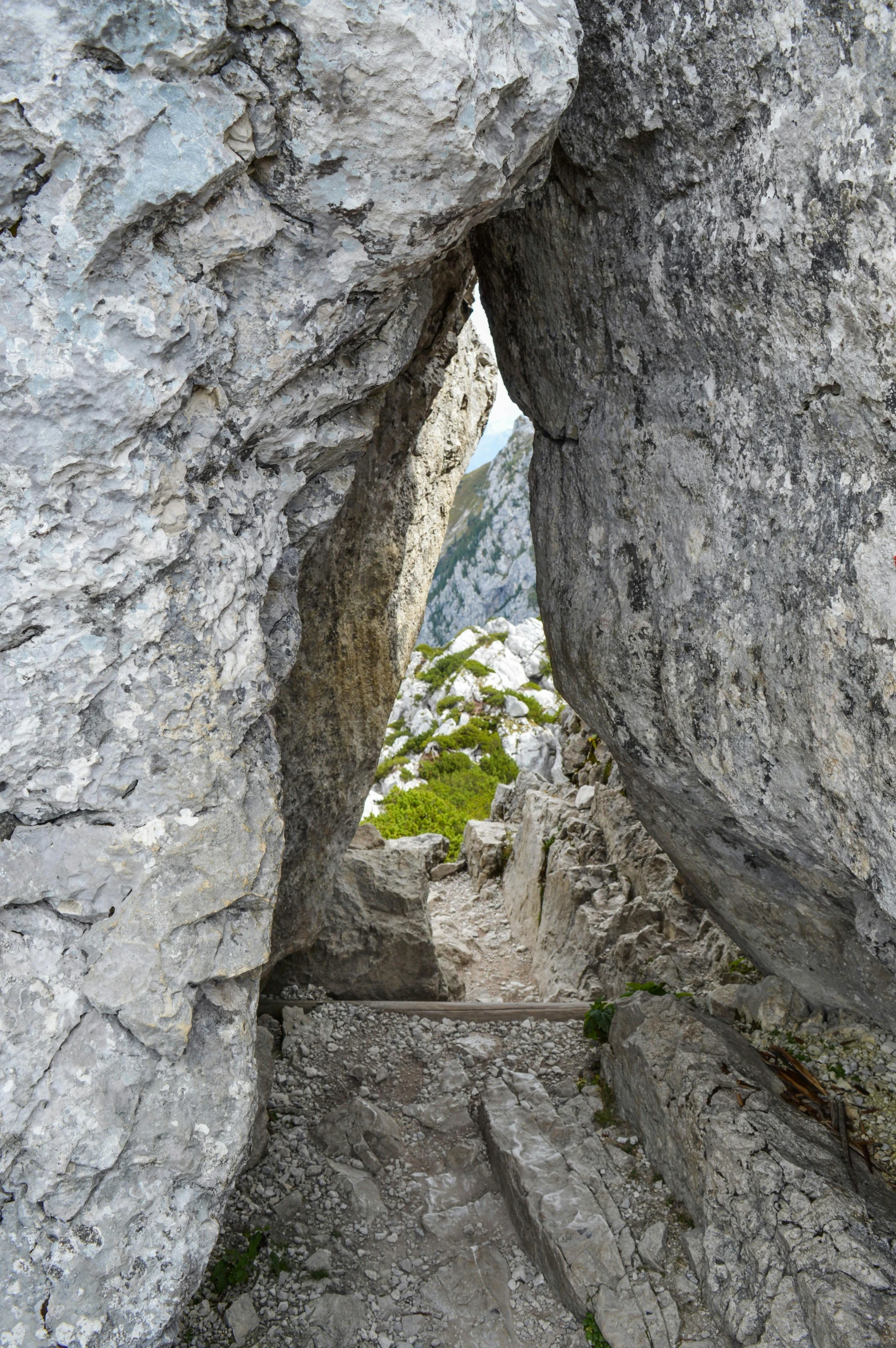 a person climbing up the side of a large rock, by Anna Haifisch, romanticism, symmetrical doorway, hiking trail, limestone, panoramic