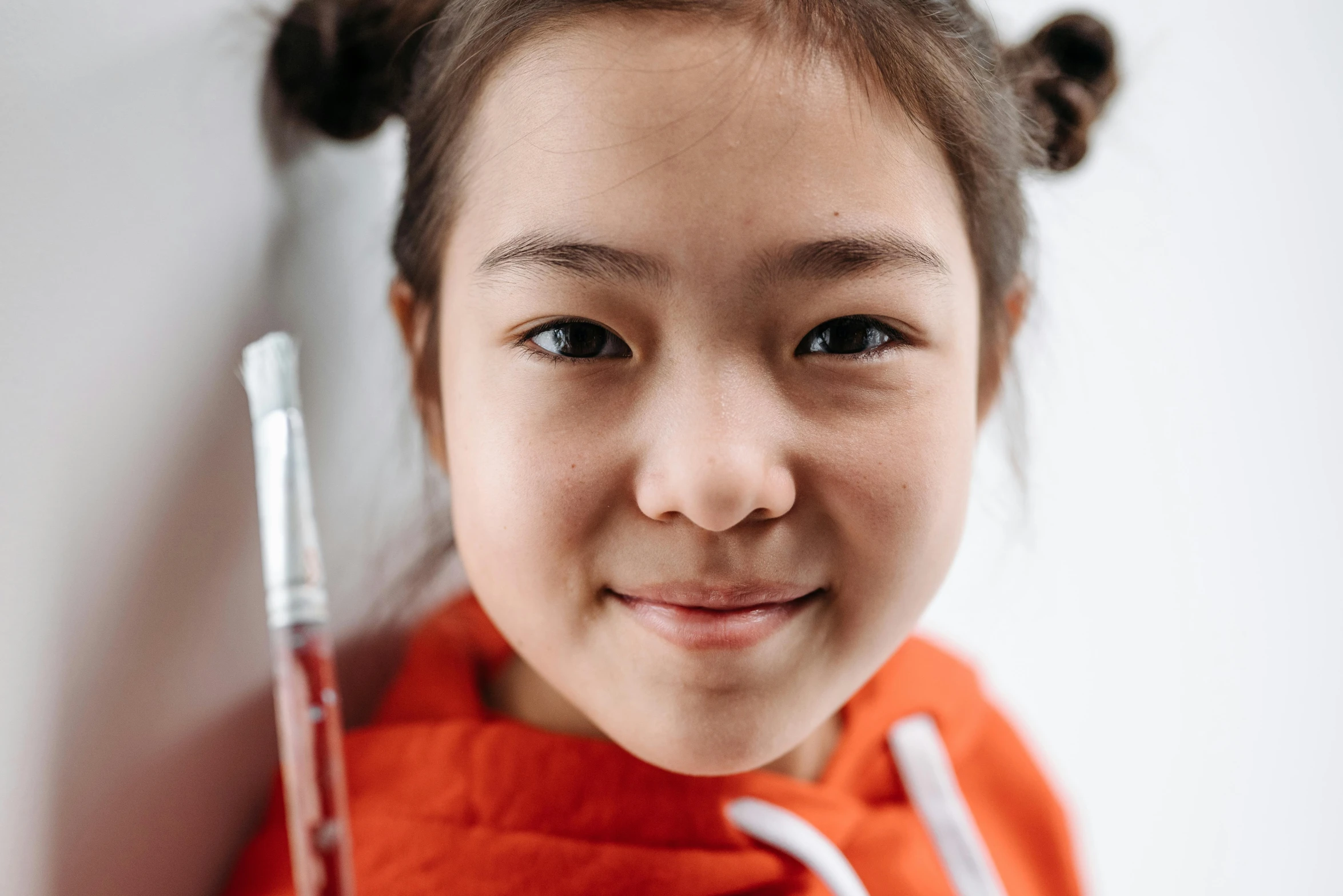 a close up of a young girl holding a toothbrush, an album cover, pexels contest winner, danube school, asian face, holding syringe, new musical instruments, smiling for the camera