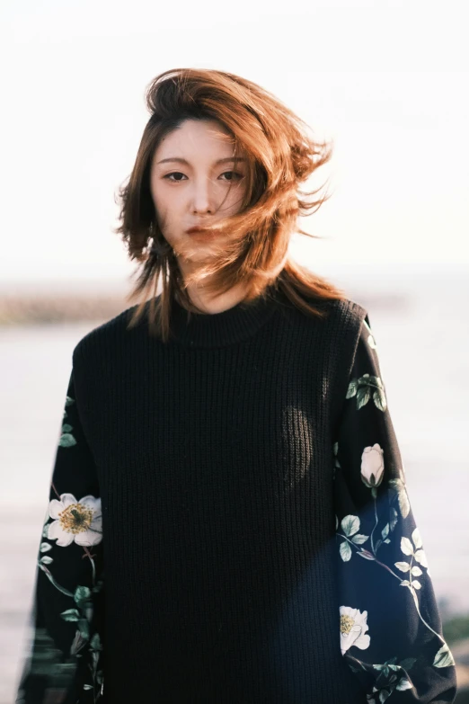 a woman standing in front of a body of water, unsplash, shin hanga, wearing a black sweater, flower storm portrait, gemma chan, あかさたなは on twitter