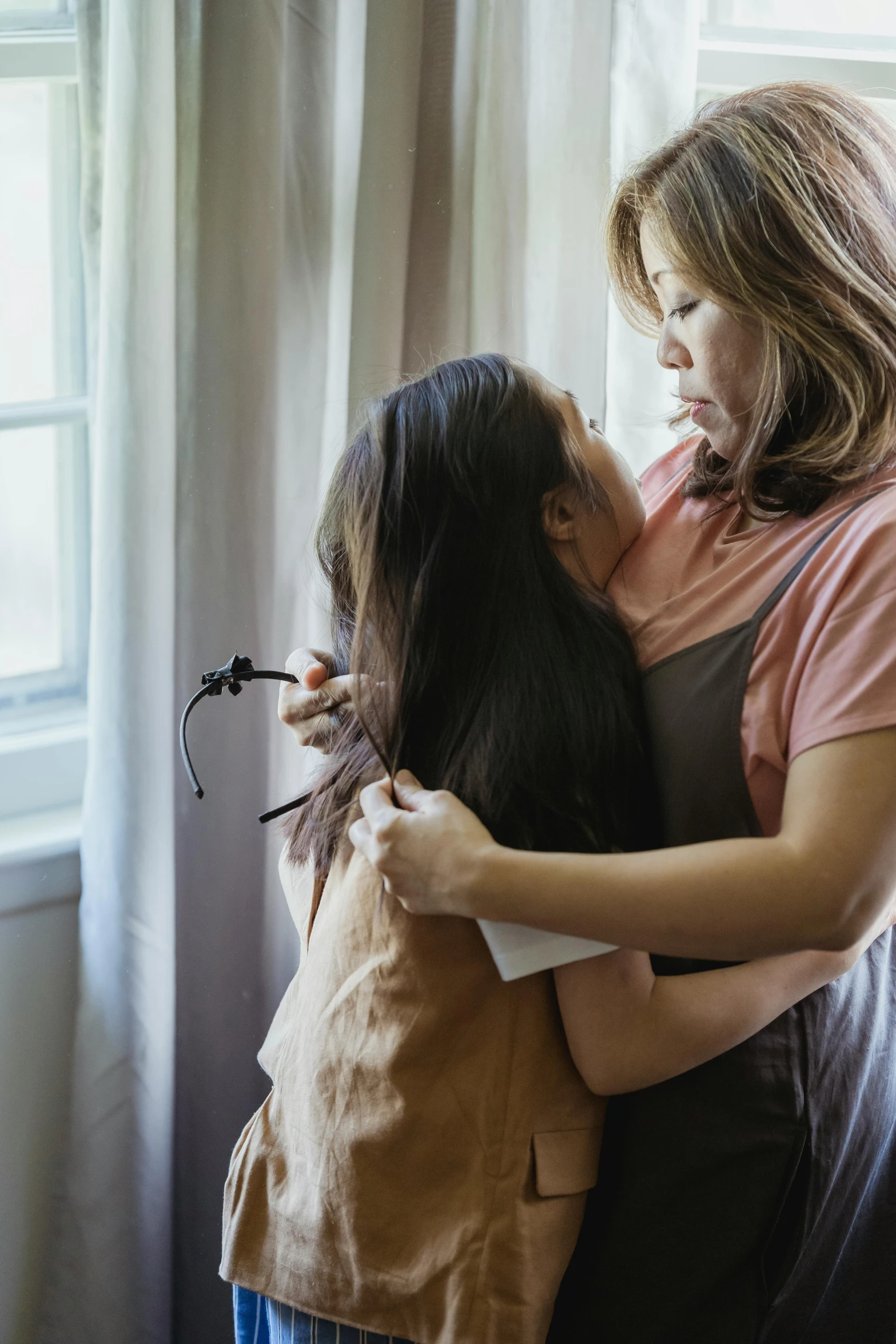 a woman hugging a little girl in front of a window, asian descent, comforting, ignant, schools