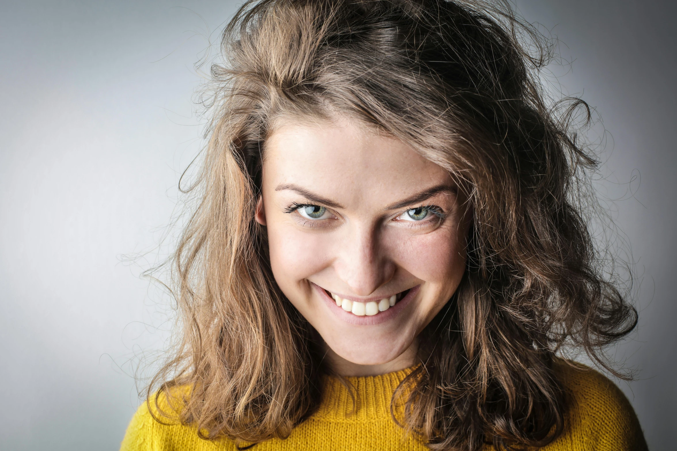 a woman in a yellow sweater holding a banana, by Matthias Stom, pexels contest winner, acting headshot, helen mcrory, smiling slightly, messy hair bedhead