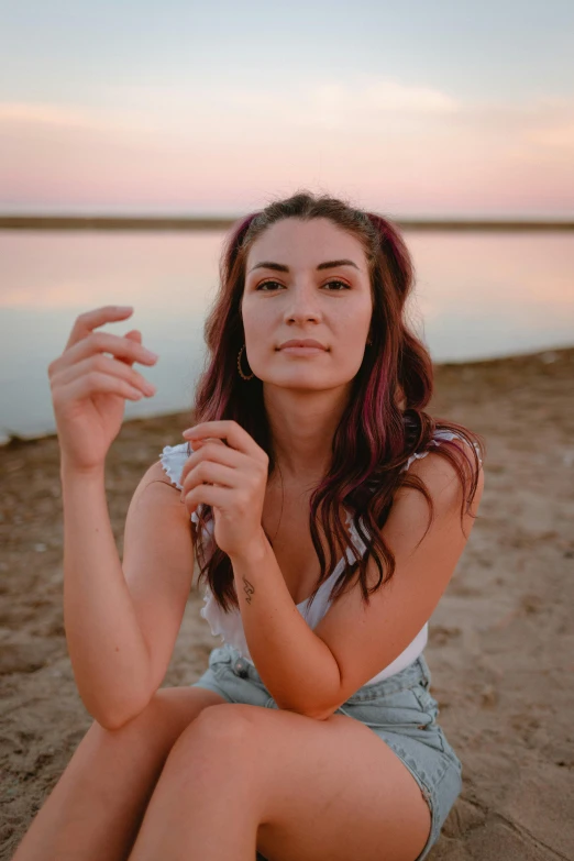 a woman sitting on a beach holding a cigarette, a portrait, trending on pexels, pink golden hour, lake, kailee mandel, high quality photo