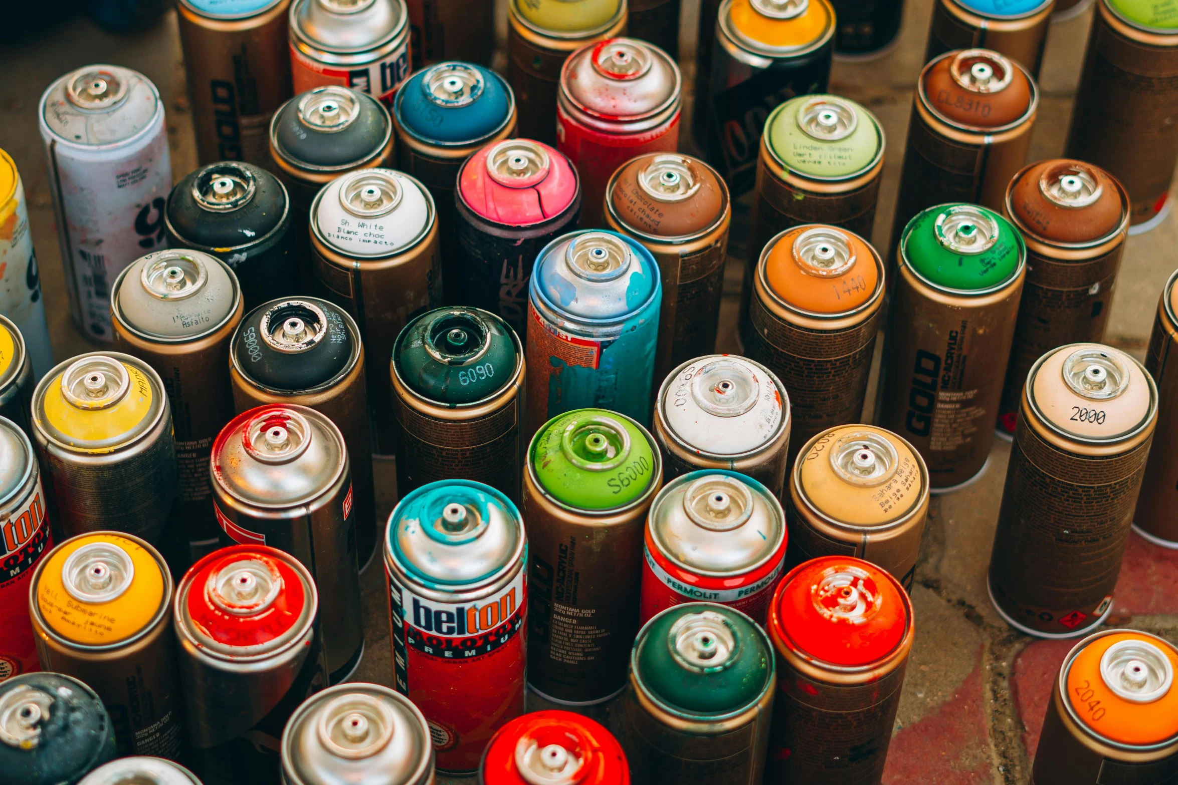 a bunch of spray cans sitting on top of a table, an airbrush painting, unsplash, 🎨🖌, multicolor, hyperdetailed, toronto