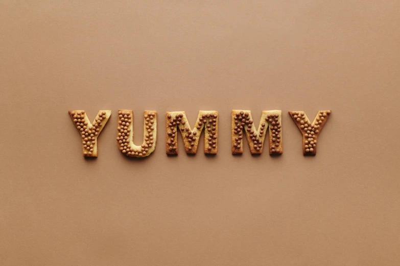 the word yummy spelled in gold letters, by Caroline Mytinger, trending on pexels, brown, military, trypophobia, mummy