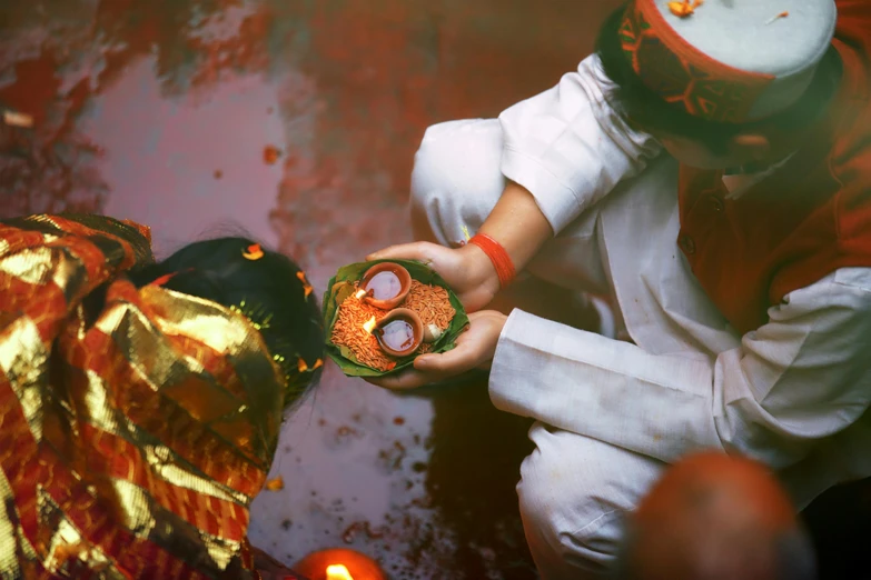 a close up of a person holding a plate of food, by Julia Pishtar, pexels contest winner, hurufiyya, submerged temple ritual scene, red and orange color scheme, holding each other hands, 🦩🪐🐞👩🏻🦳