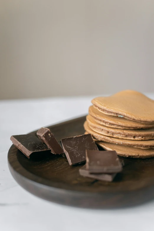 a plate of cookies and chocolate on a table, mingei, flat pancake head, dark. no text, stacked image, birch