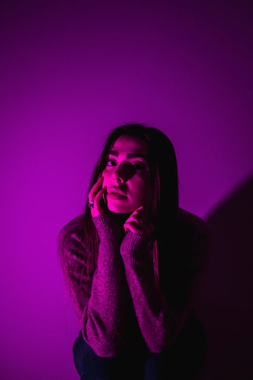 a woman standing in front of a purple wall, a black and white photo, inspired by Elsa Bleda, pexels, bright pink purple lights, sorrow intense likely, photo of young woman, in a pitch black room