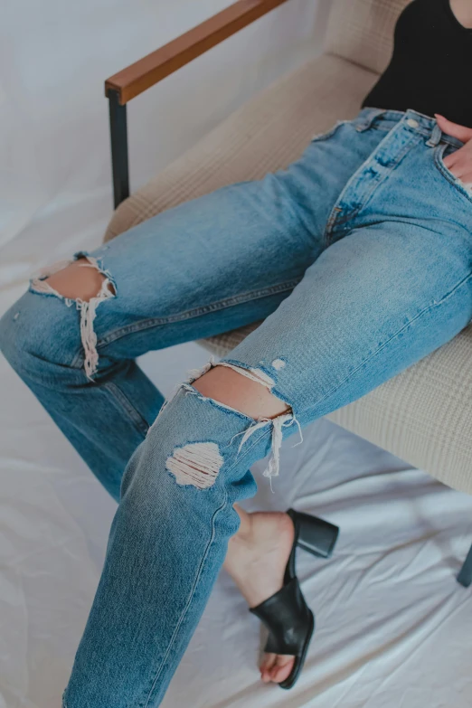 a woman that is laying down on a bed, inspired by Elsa Bleda, trending on unsplash, renaissance, ripped jeans, sitting on a chair, detailed product image, view(full body + zoomed out)