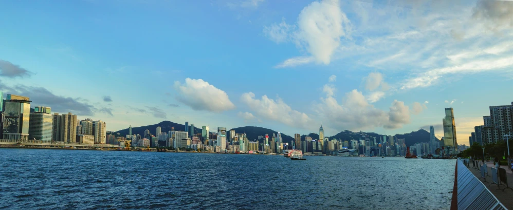 a large body of water surrounded by tall buildings, by Charlotte Harding, pexels contest winner, hong kong, blue sky, island in the background, slide show