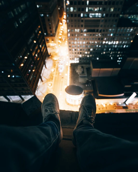 a person standing on a ledge in the middle of a city at night, a picture, happening, detailed shot legs-up, looming over you, instagram post, high towers