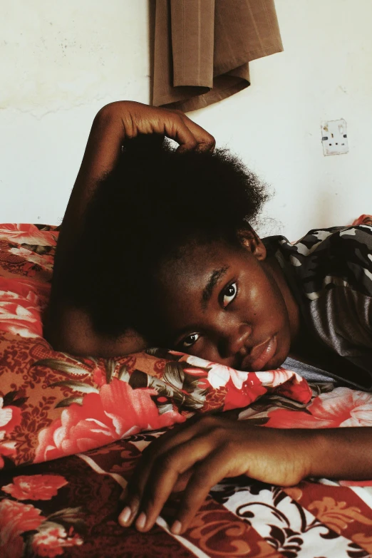 a close up of a person laying on a bed, by Lily Delissa Joseph, black teenage girl, looking confident, thinking pose, black people