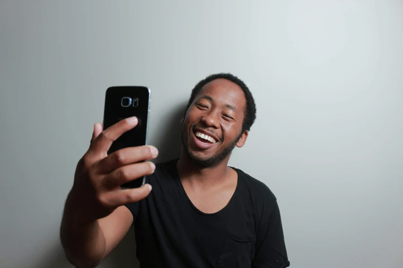 a man taking a selfie with his cell phone, pexels contest winner, large black smile, plain background, avatar image, childish gambino