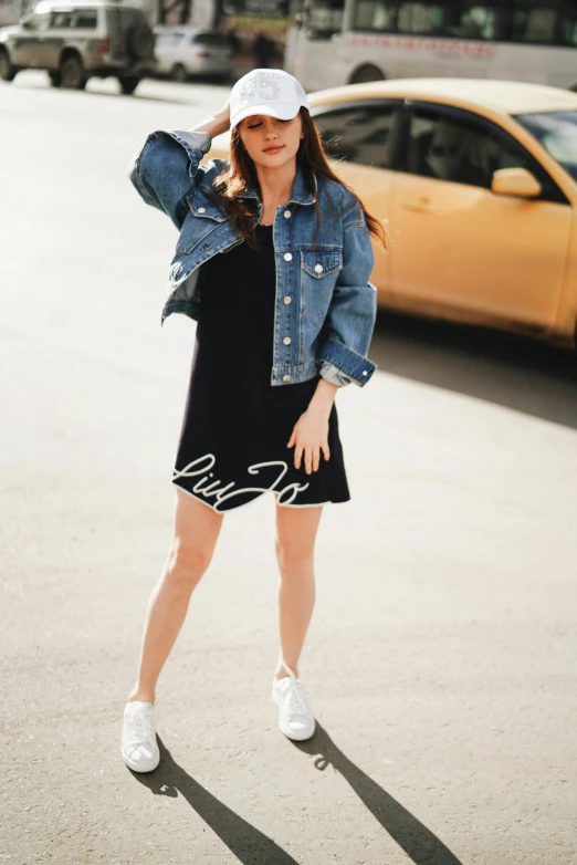 a woman standing in the middle of a street, trending on pexels, lyco art, denim jacket, in white lettering, wearing a black dress, 15081959 21121991 01012000 4k