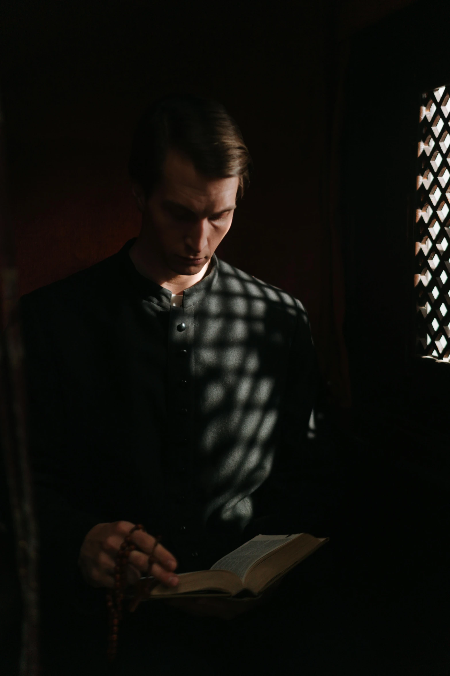 a man reading a book in a dark room, an album cover, inspired by Eliseu Visconti, unsplash, renaissance, standing in a church, handsome man, perfectly lit. movie still, hammershøi