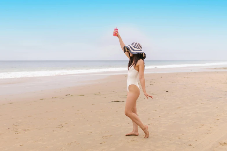 a woman standing on top of a sandy beach, awkwardly holding red solo cup, woman with hat, charli xcx, dancing gracefully