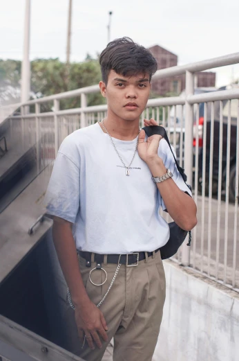 a man in a blue shirt and khaki pants, a colorized photo, inspired by Ryan Yee, trending on pexels, renaissance, young wan angel, wearing steel collar, streetwear, boyish face