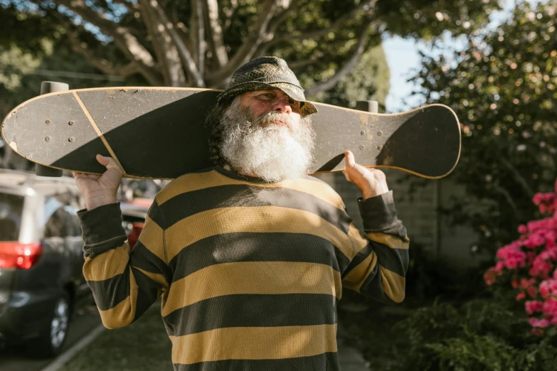 a man with a long beard holding a skateboard, by Winona Nelson, pexels contest winner, grandfatherly, australian, where's wally, yellowed with age