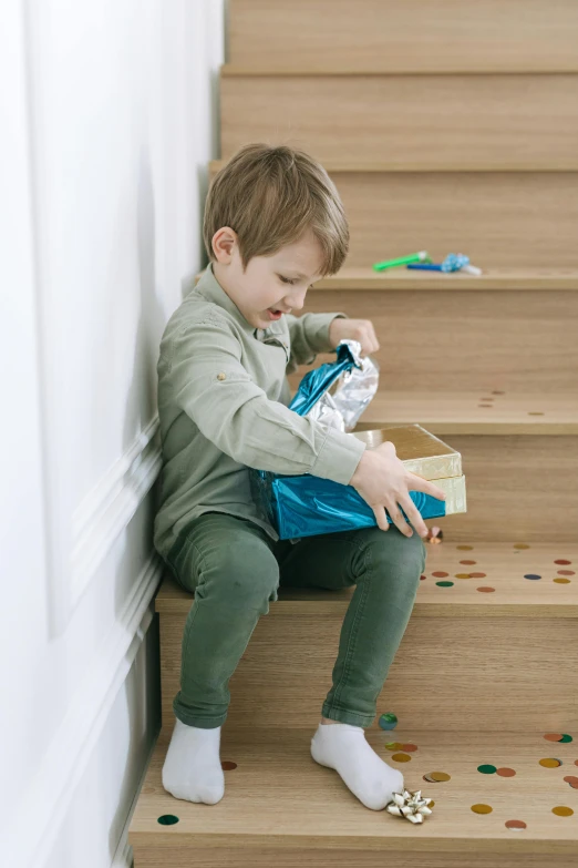 a little boy that is sitting on some stairs, toy package, rubbish, having a snack, promo image