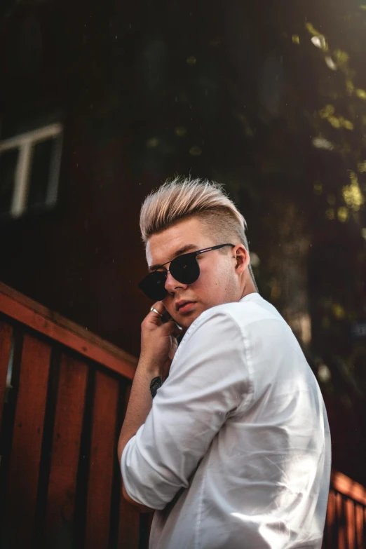 a man in a white shirt and sunglasses talking on a cell phone, by Austin English, trending on pexels, albino hair, pompadour, liam brazier and nielly, confident pose