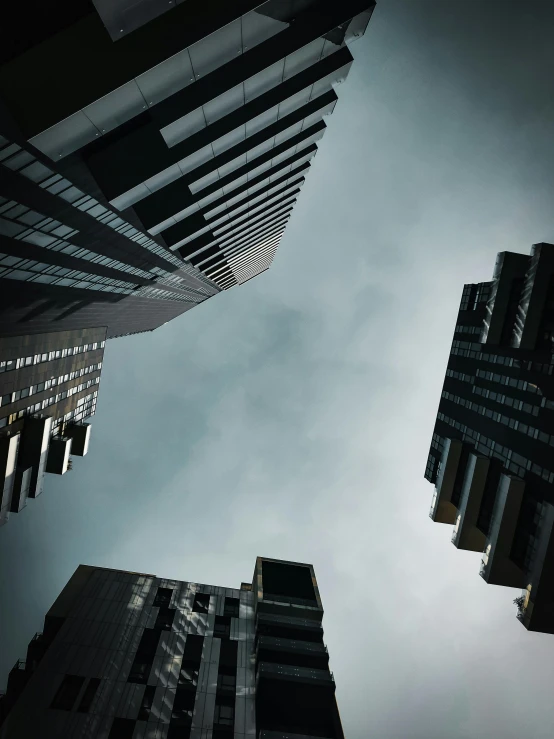 a group of tall buildings sitting next to each other, by Adam Rex, pexels contest winner, brutalism, floating into the sky, ignant, dark futuristic city, worm\'s eye view