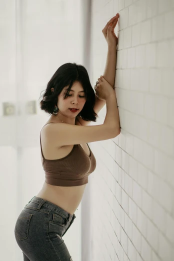 a woman leaning against a white brick wall, a picture, by Tan Ting-pho, unsplash, wearing a sexy cropped top, brown:-2, indoor picture, with a bob cut
